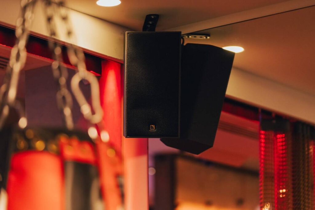 Hidden behind chain curtains, the gym area features two black ceiling-mounted L-Acoustics X6i speakers.